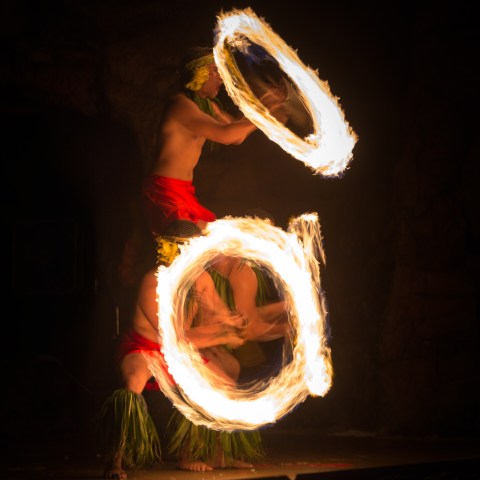 Three men spinning their fire knives creating a pyramid