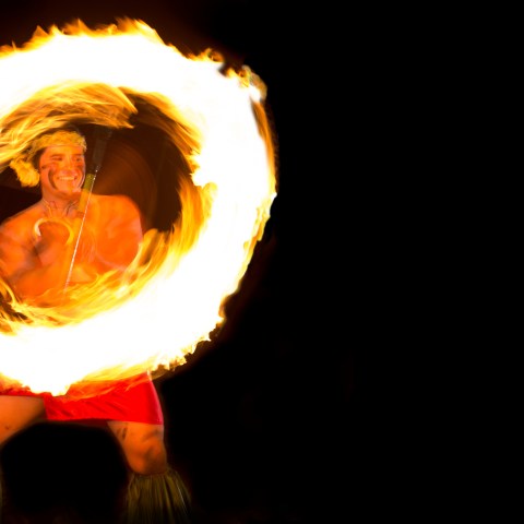 A man spinning fire while smiling
