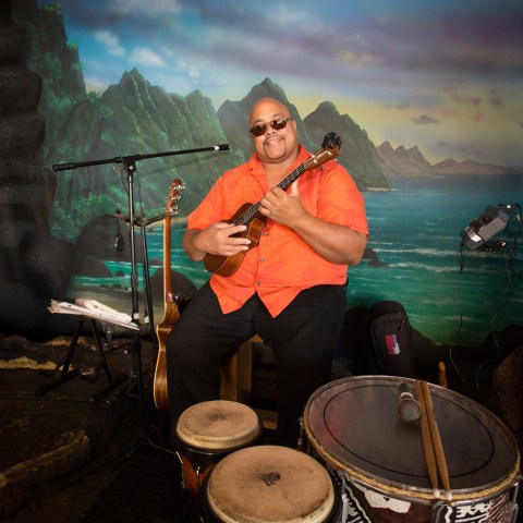 A man holding a guitar while sitting on stage