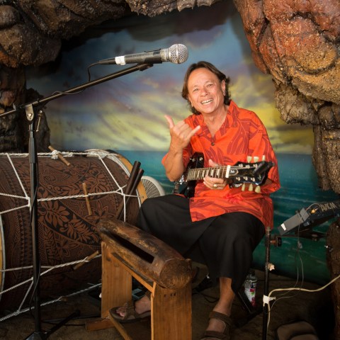 A man throwing up the haka sign while holding a guitar